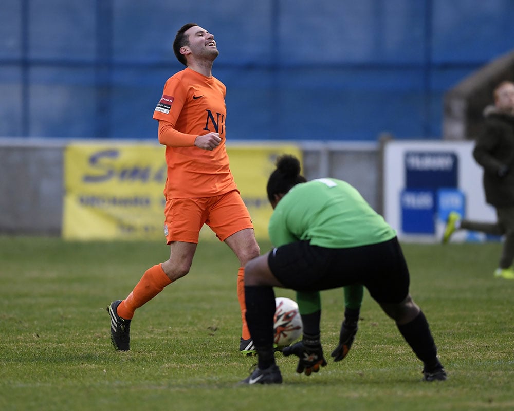 footballer smiles as he misses a chance