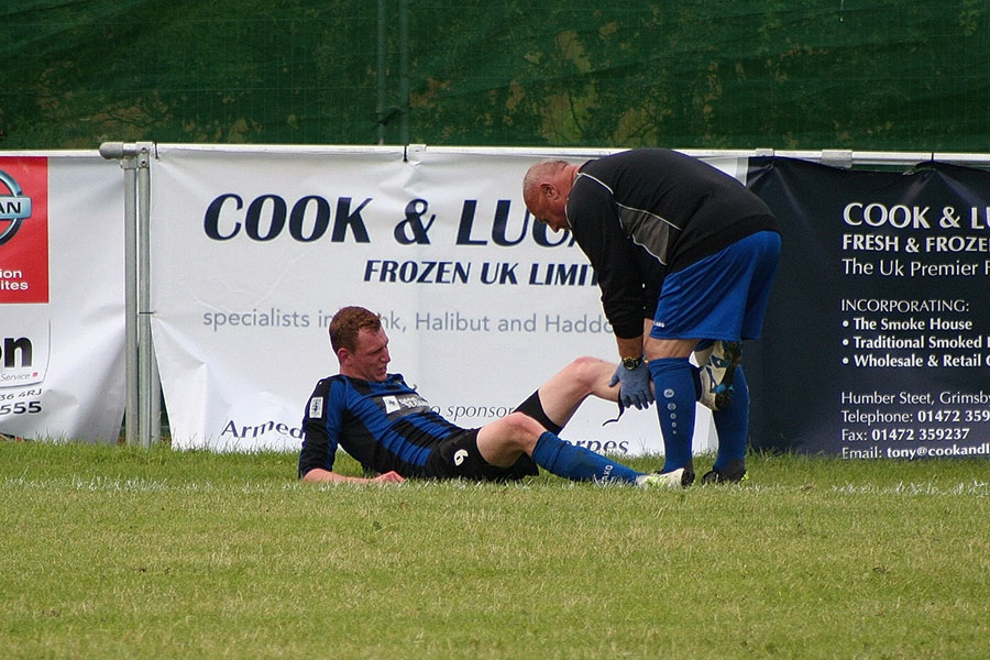 footballer receiving treatment from physio for injury